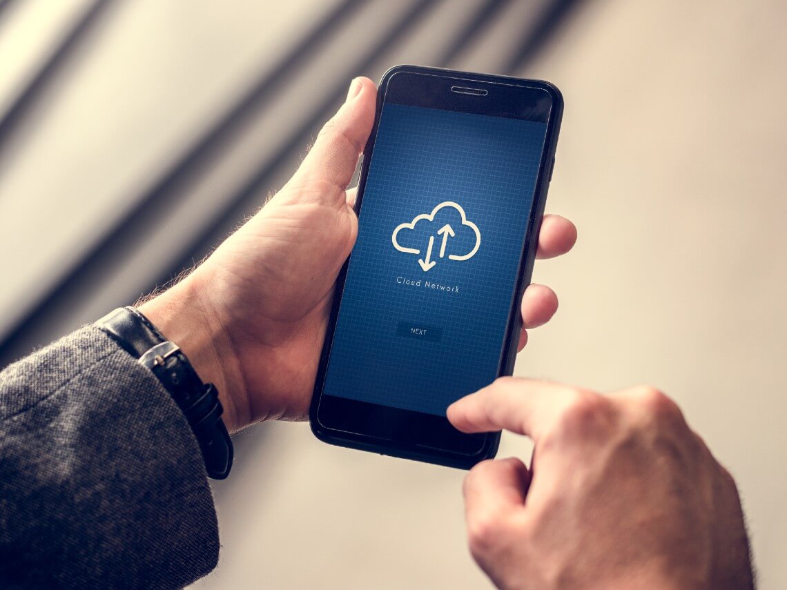 Man holding phone with screen showing cloud network.